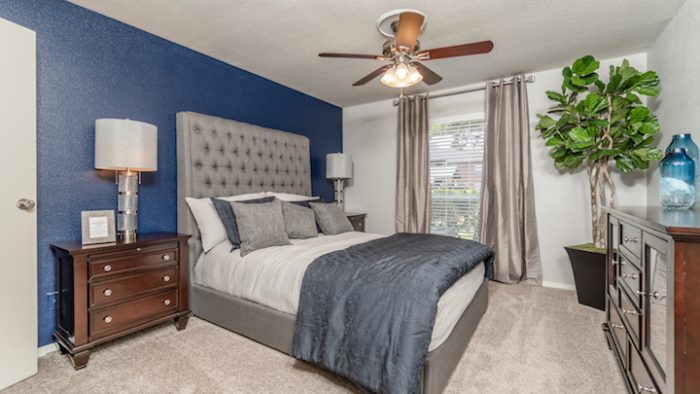 a bedroom with blue walls and a ceiling fan at The Westmount at Copper Mill